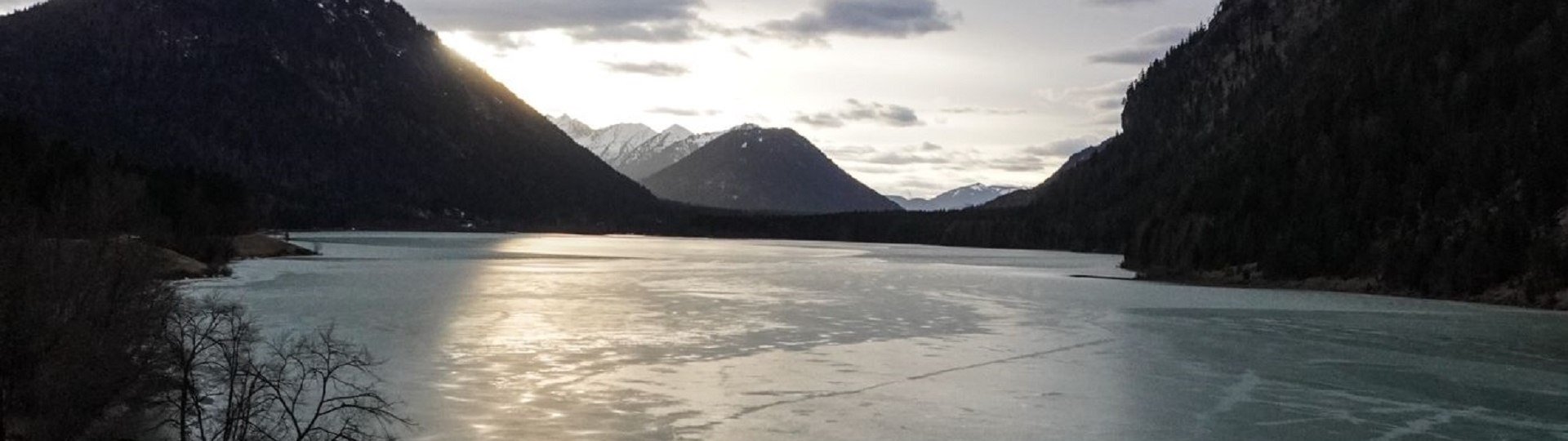 Das Bild zeigt eine mystische Stimmung des Sylvensteinsees im Winter - scherenschnittartig ragen die Berge links und rechts des Sees auf., © Landratsamt Bad Tölz-Wolfratshausen|Foto: A. Fischer